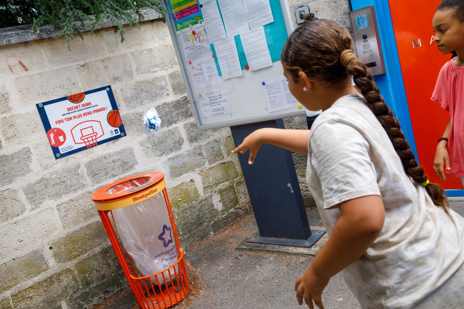 Un enfant lance un déchet dans la corbeille basket.