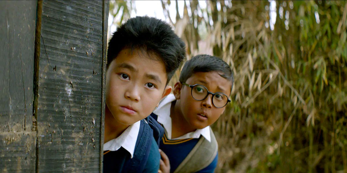 Extrait du film Boong, montrant deux petits garçons, se cachant derrière une porte