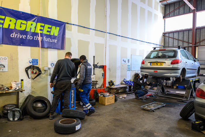 voiture surélevée, outils, ouvriers, pneus dans le garage solidaire