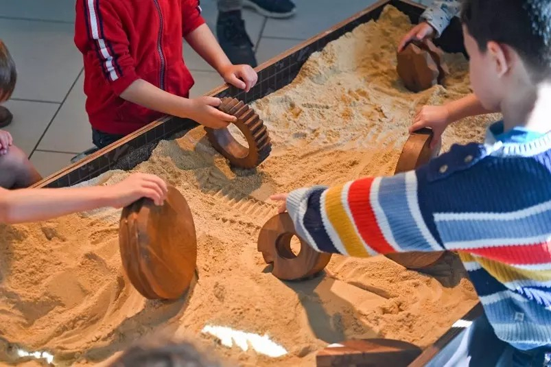 des enfants jouent avec des formes dans un bas à sable 