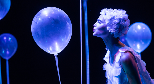 Jeune femme en costume, soufflant sur un ballon